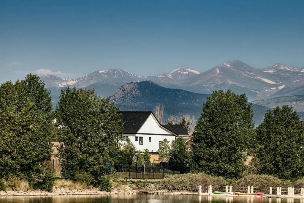 House and trees with mountains in the background under a clear sky