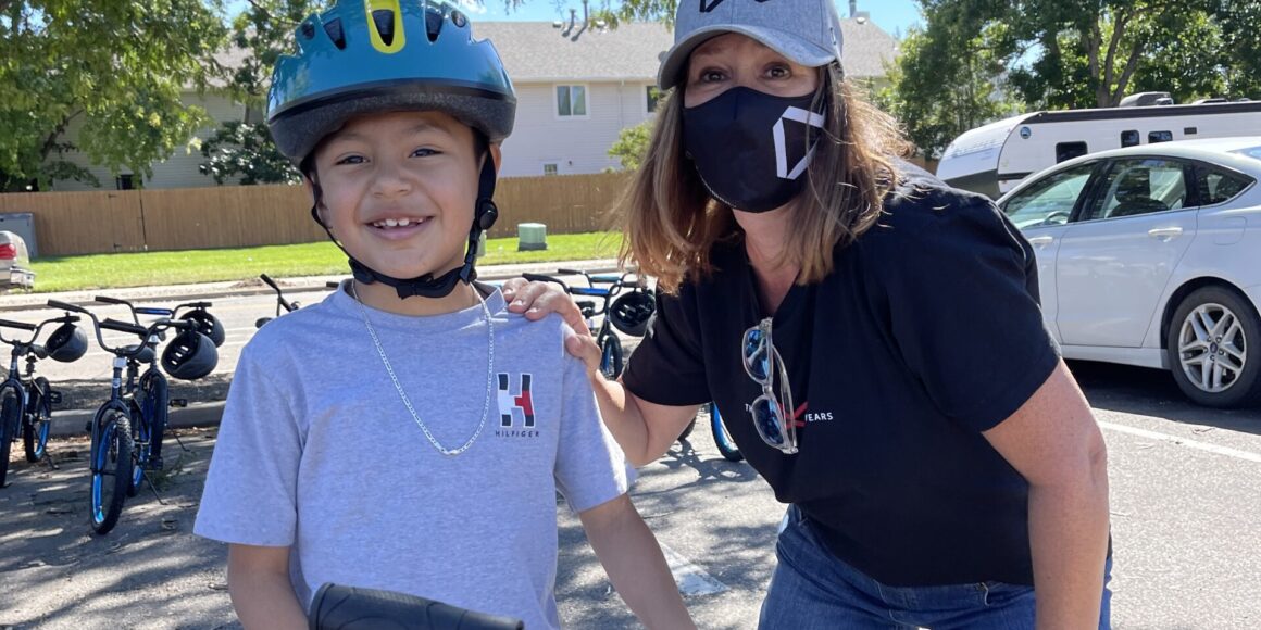 Women in McWhinney branded mask posing with elementary school student during the Wist for Wheels event