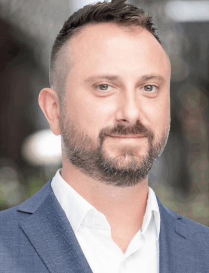 Jason-Cruce.png, man in a blue suit smiling gently, blurred background
